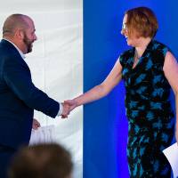Gentleman walking on to stage and shaking woman's hand
